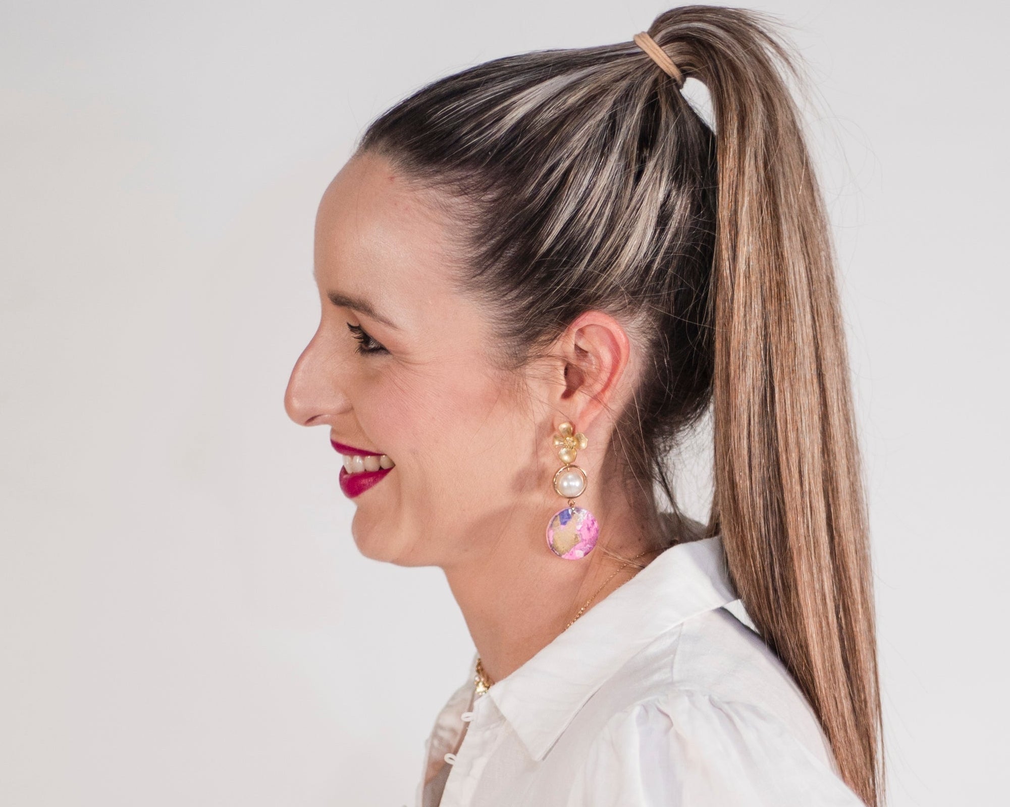 Woman wearing a white blouse and blue jeans against a plain background