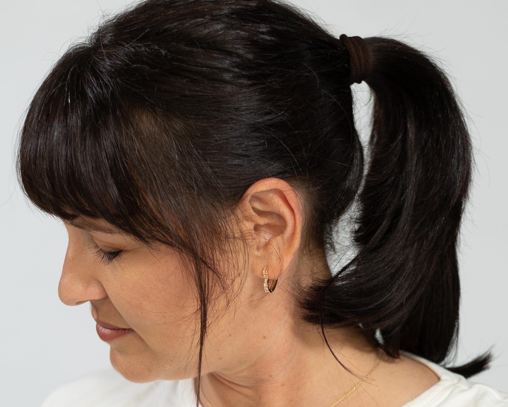 Woman wearing a white top and blue jeans against a plain background