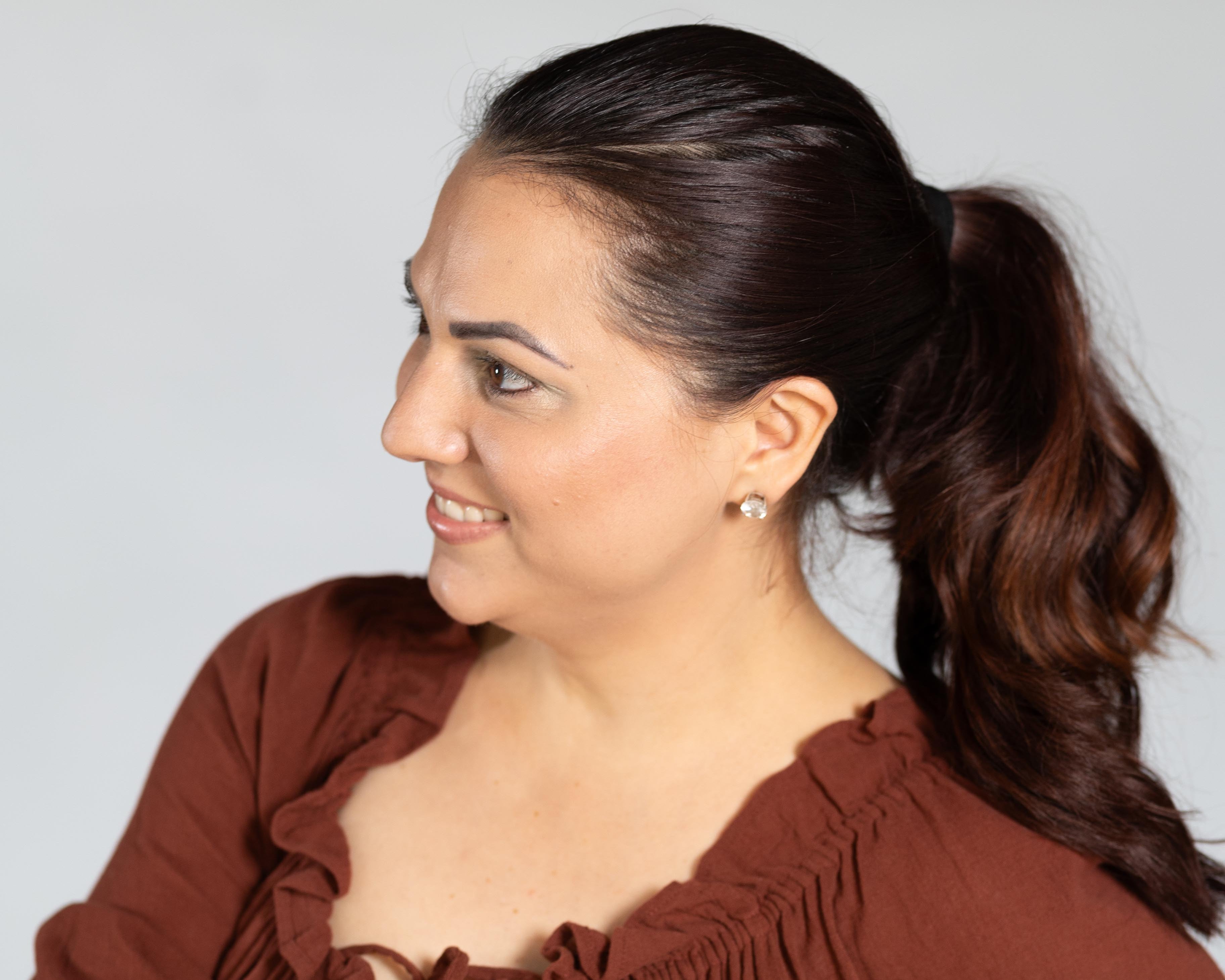 Woman wearing a brown blouse against a plain background
